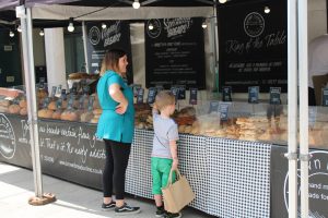 Child and staff buying pastries at campus market stall