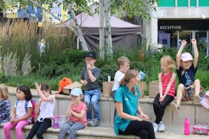 Children and staff sitting on campus squares