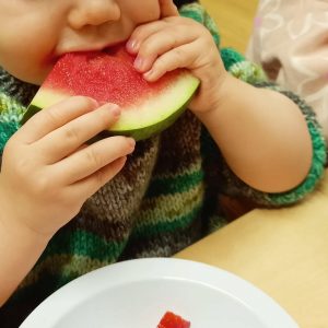 Young child eating a slice of watermelon at a table